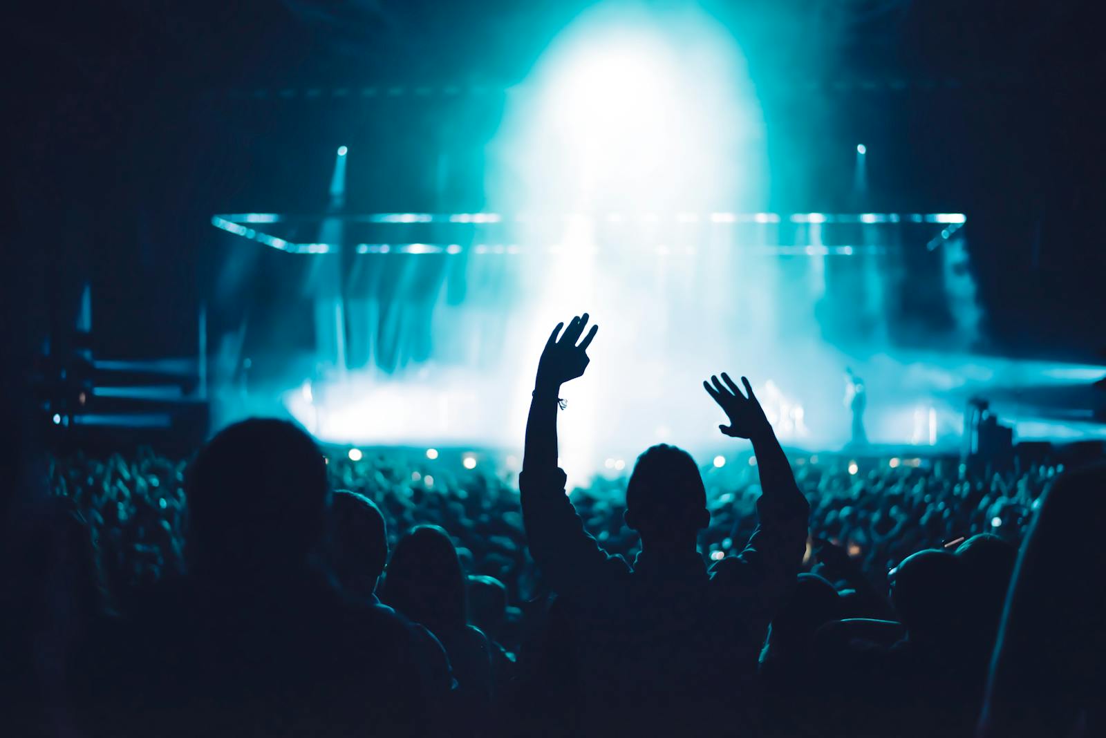 Crowd at a festival with hands raised against bright stage lights